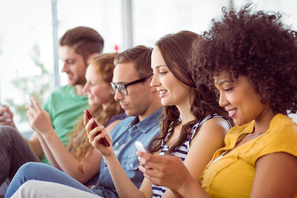 Imagen de cuatro estudiantes riendo mirando sus teléfonos con camisetas de varios colores. Contenido orgánico para negocios Emprendedores hispanos en EE.UU. Marketing digital para pequeños negocios Estrategias de SEO para negocios hispanos Desarrollo de marca para emprendedores hispanos Estrategias de marketing para hispanos Cómo hacer crecer un negocio con contenido orgánico Estrategias de crecimiento para pequeños negocios Marketing de contenidos para emprendedores hispanos Desarrollar una marca como emprendedor hispano